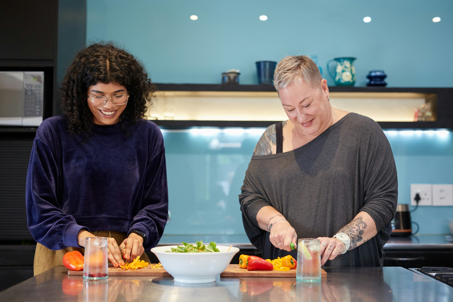 a-couple-of-women-standing-in-a-kitchen-preparing-food